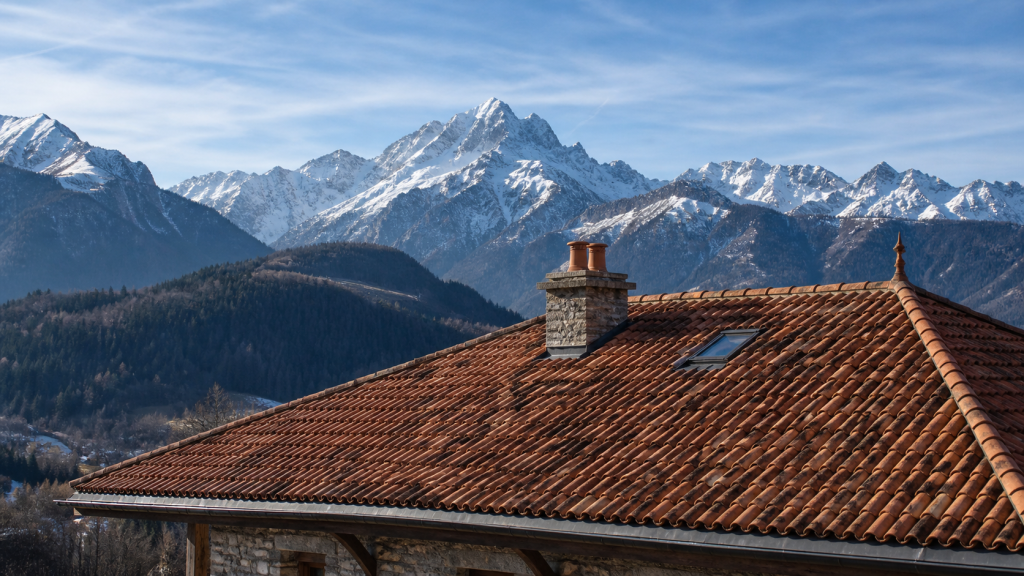 Toiture en tuile terre cuite face aux montagnes enneigées en Savoie